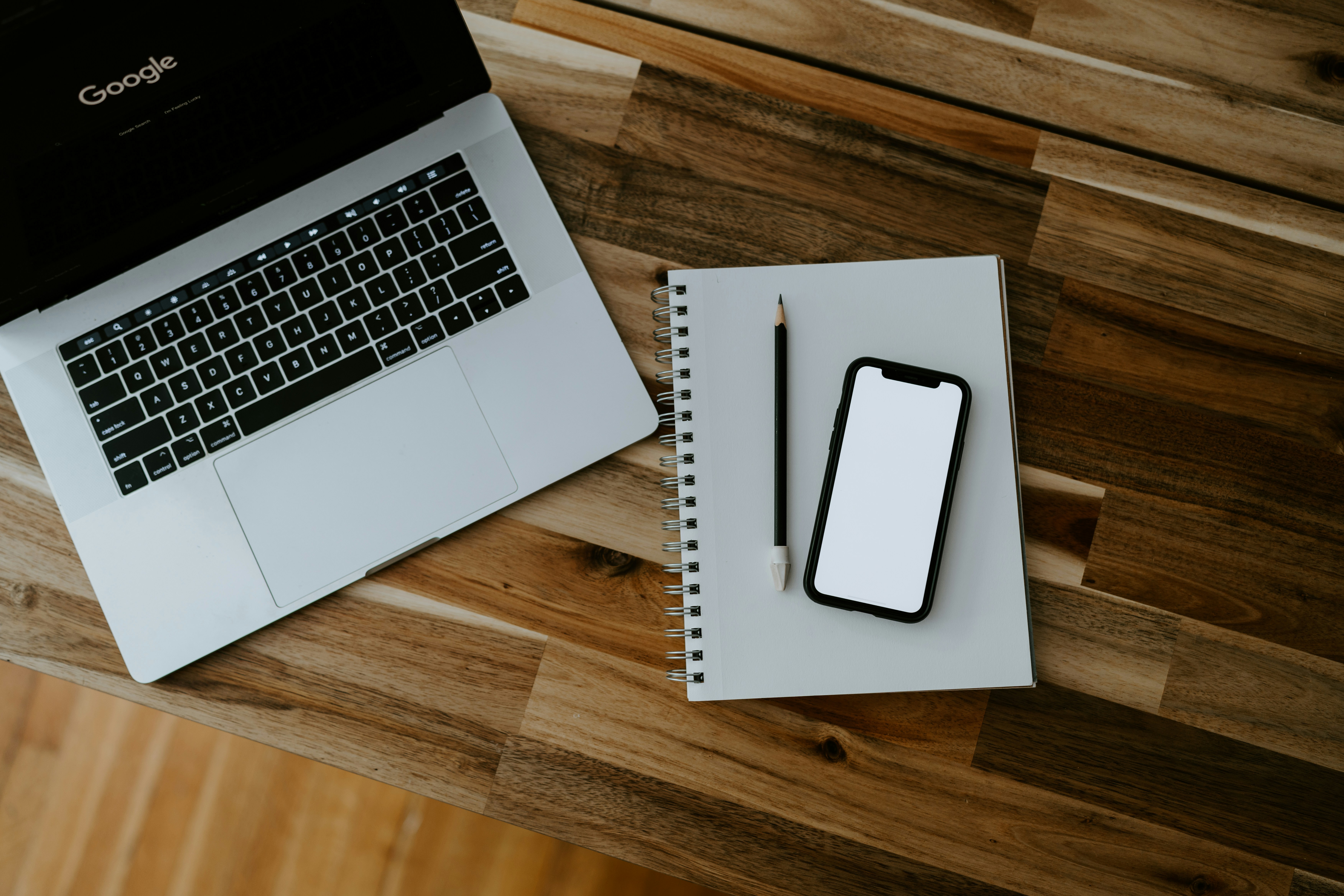 A notebook and an iPhone on a wooden table, representing data moving from one quiet place to another.