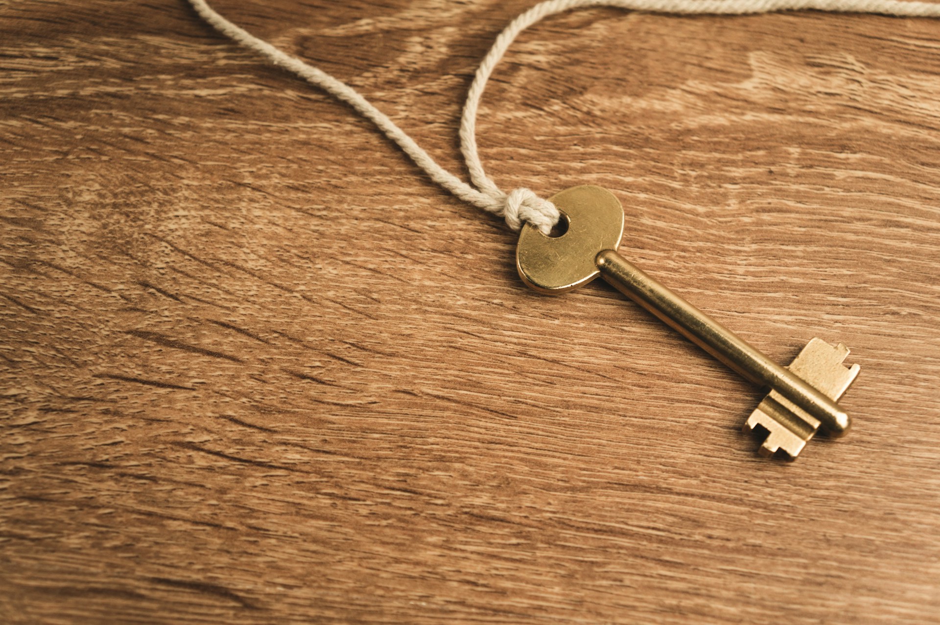 A small key resting on a wooden surface, representing a spare key kept somewhere safe.