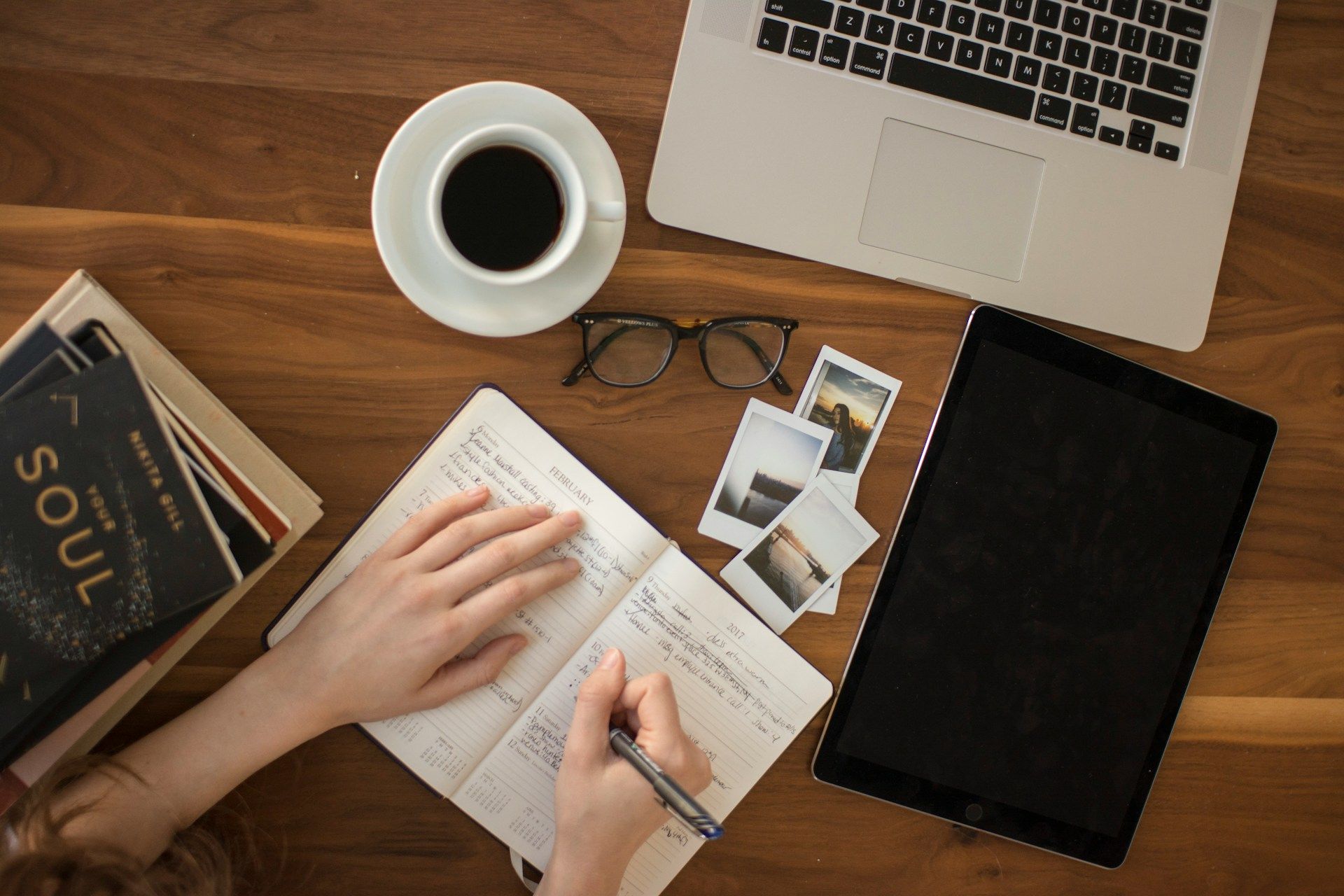 A person writing a personal planning note in a notebook at a desk.
