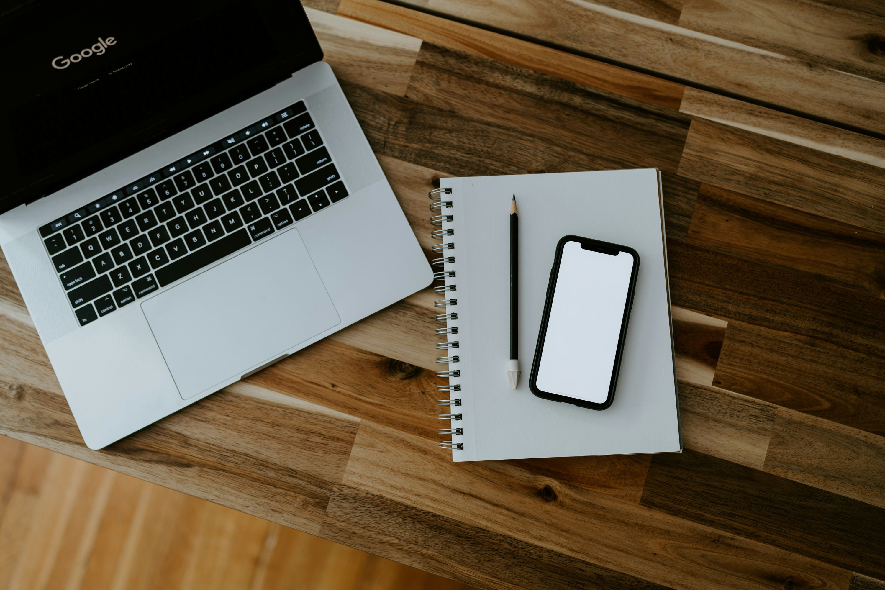 A notebook and an iPhone on a wooden table, representing data moving from one quiet place to another.