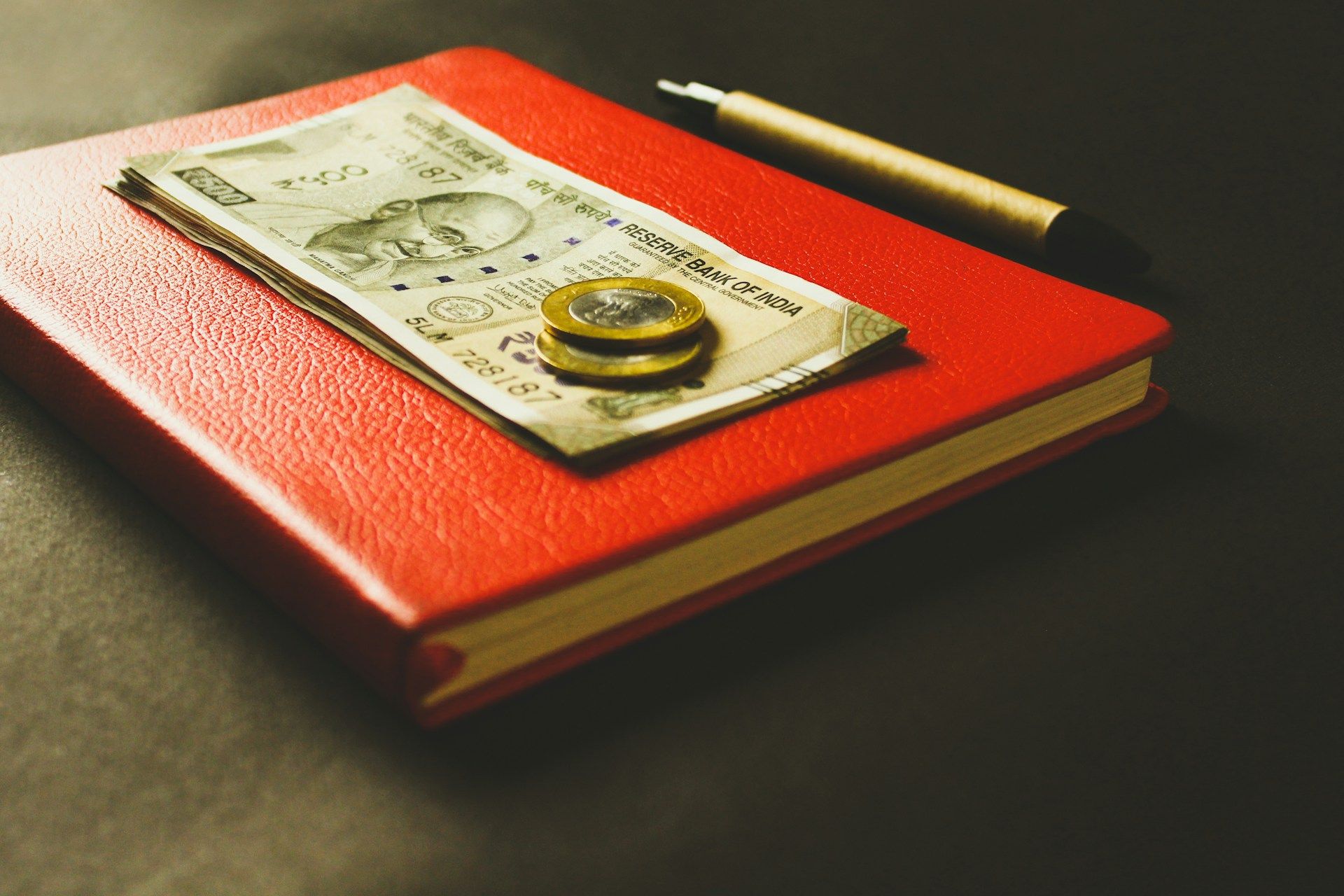 Indian currency notes beside a handwritten ledger, representing family savings.