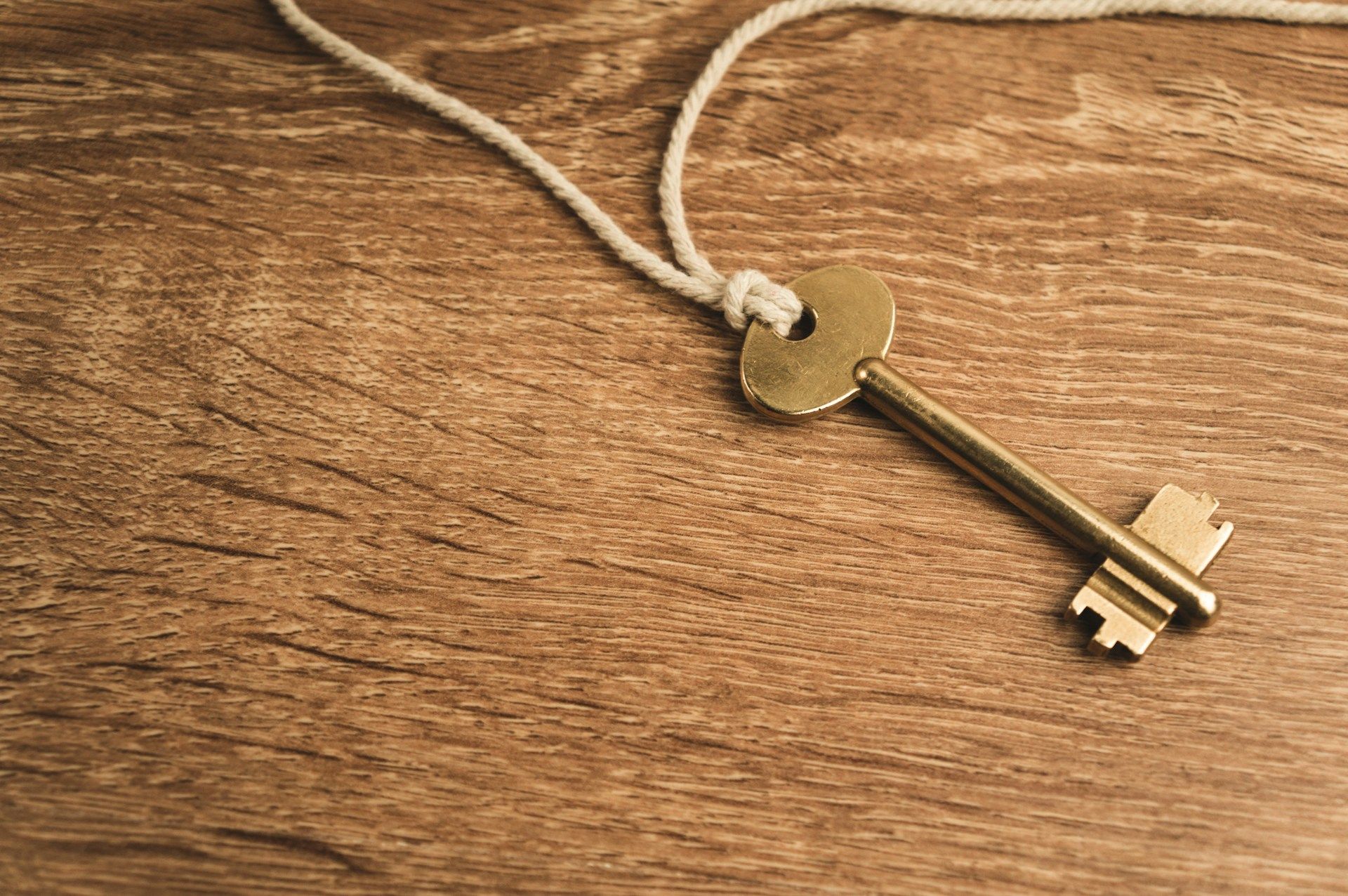 A small key resting on a wooden surface, representing a spare key kept somewhere safe.